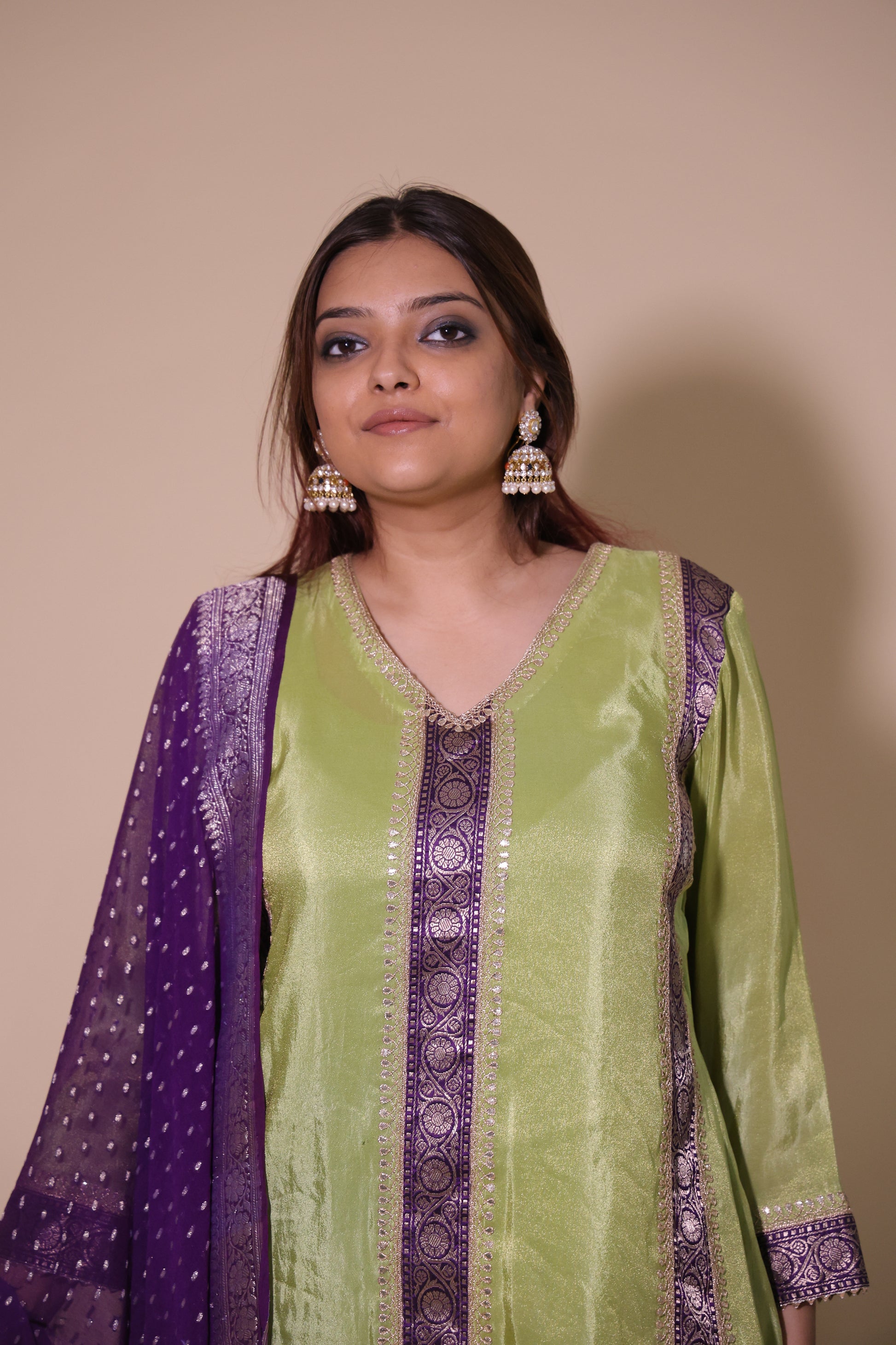 Woman wearing a green and purple traditional outfit against a beige background.Tissue Silk Banarasi Salwar Suit with Dori Marodi &amp; Georgette Banarasi Dupatta