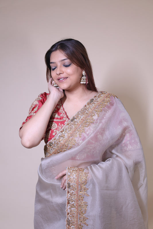 Woman wearing a traditional outfit with gold embroidery on a plain background Beige Organza Saree with Red Blouse
