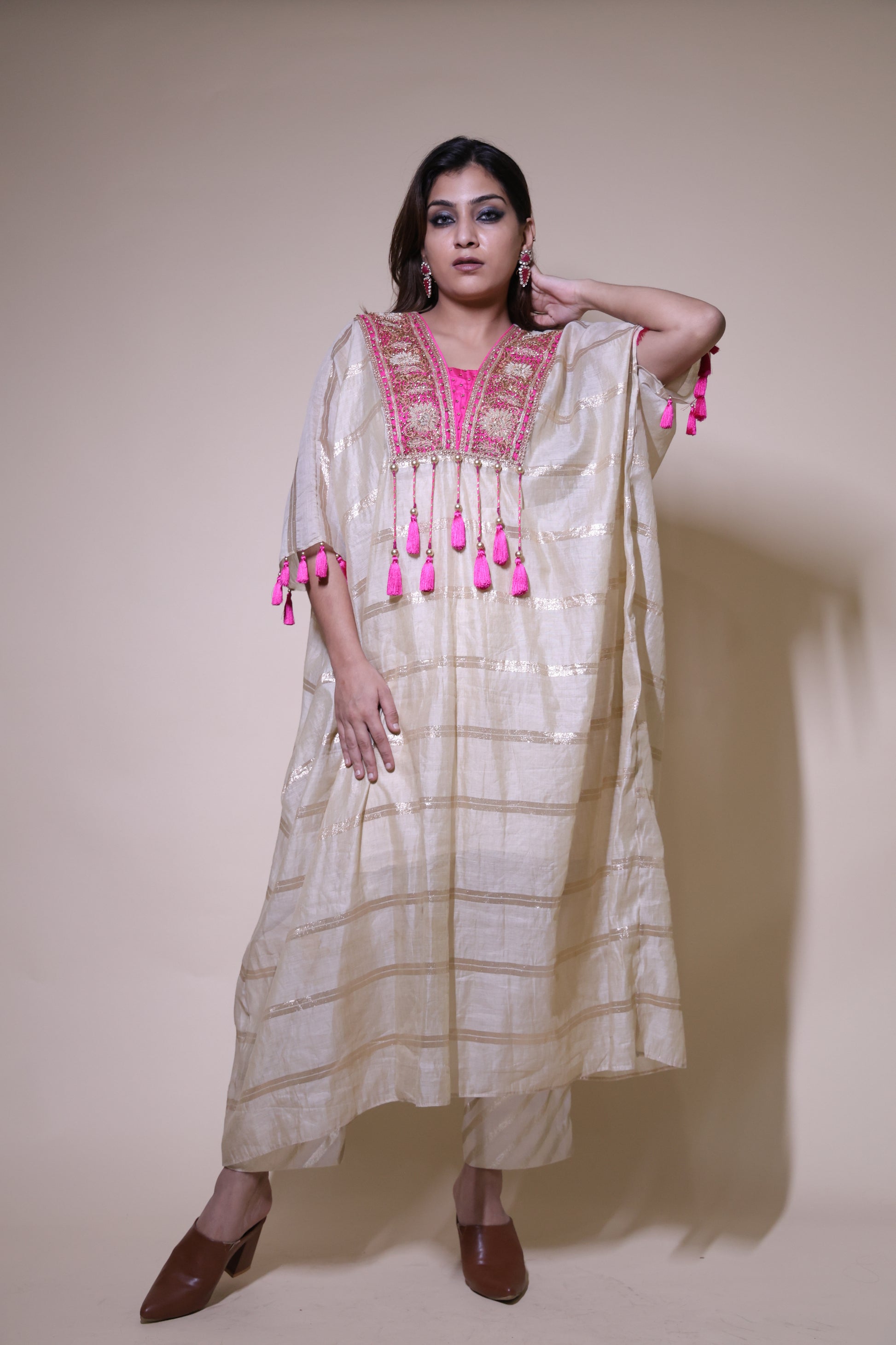 Woman wearing a traditional outfit with pink accents on a plain background Beige and pink chanderi silk kaftaan with zardozi work