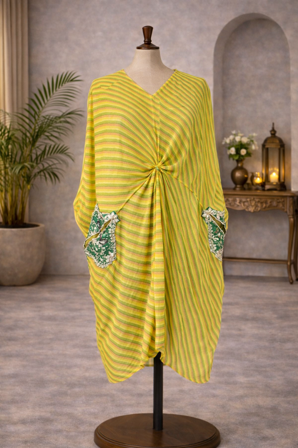 Yellow striped dress on a mannequin against a gray wall with decorative elements. Blue Green kaftaan with gotta patti work