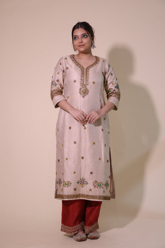 Woman wearing a traditional outfit with intricate designs on a beige background.
Cream Heavy Banarasi Kurta with Copper Dori Tari Work &amp; Red Palazzo