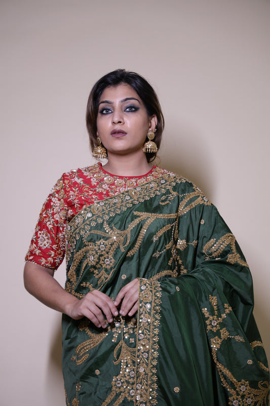Woman wearing a green and red embroidered traditional outfit on a plain background Green Dori–Marori Bridal Saree with Red Jaal Blouse