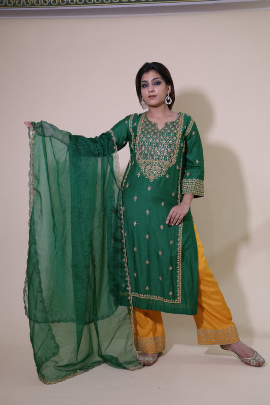 Woman wearing a green traditional outfit with a yellow dupatta on a plain background.Green Moonga Silk Pakistani Suit