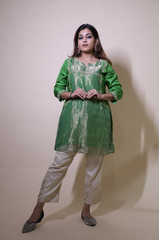 Woman wearing a green traditional outfit with white pants on a plain background Green Tissue Kurta with Gotapatti and  cream pants