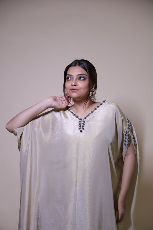 Woman wearing a white dress with a floral pattern on a plain background Off-white gold tissue  kaftaan with antique handwork