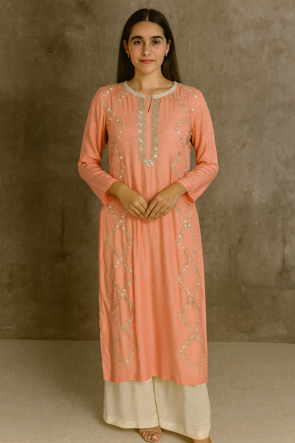Woman wearing a peach-colored kurta with intricate embroidery against a brown background Peach And Beige Layered Kurta Gown Set with Gottapatti