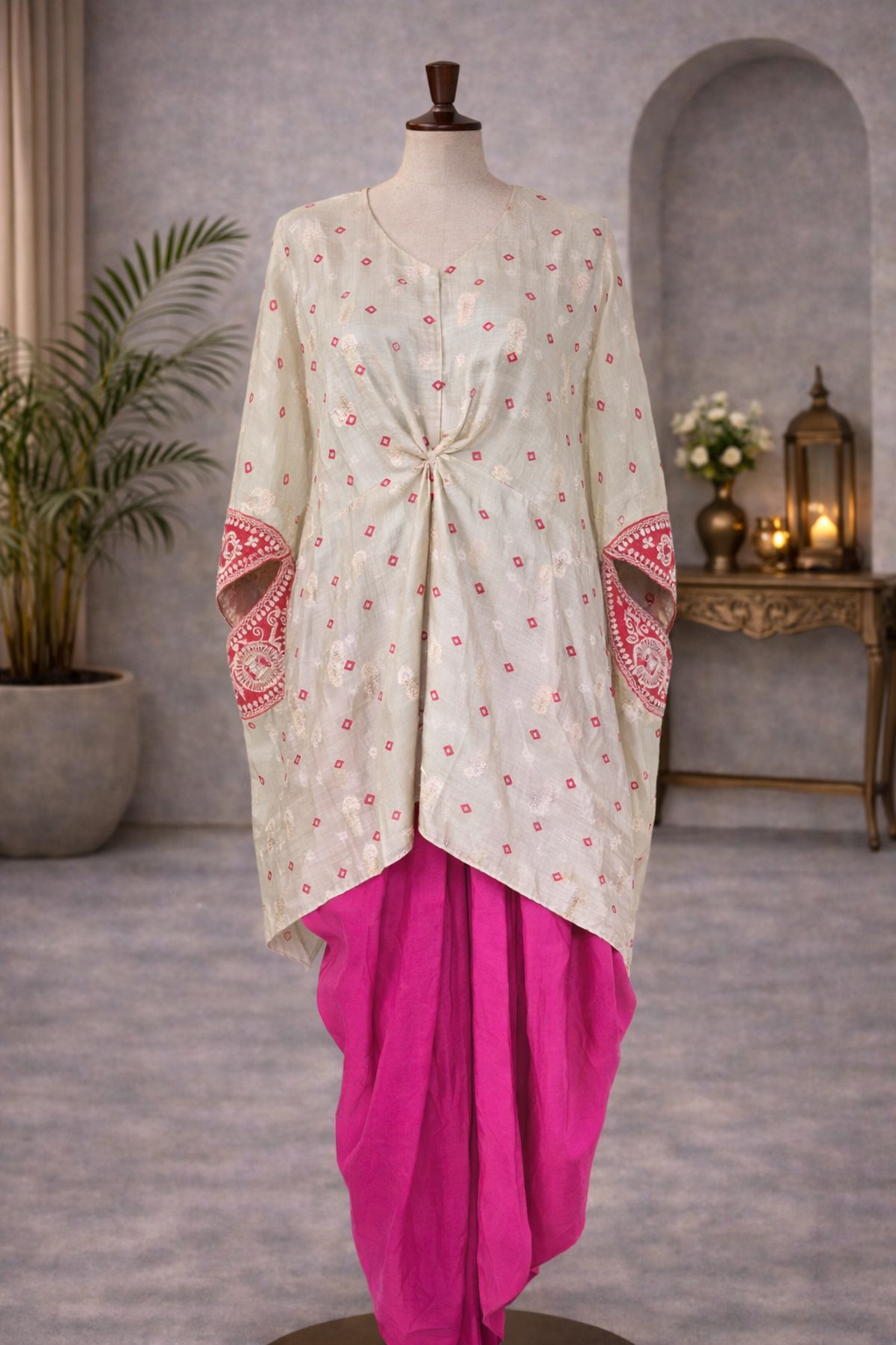Traditional outfit with a white top and pink skirt on a mannequin against a gray wall.Pink_and_grey_bandhej_gotta_patti_kaftaan_with_dhoti