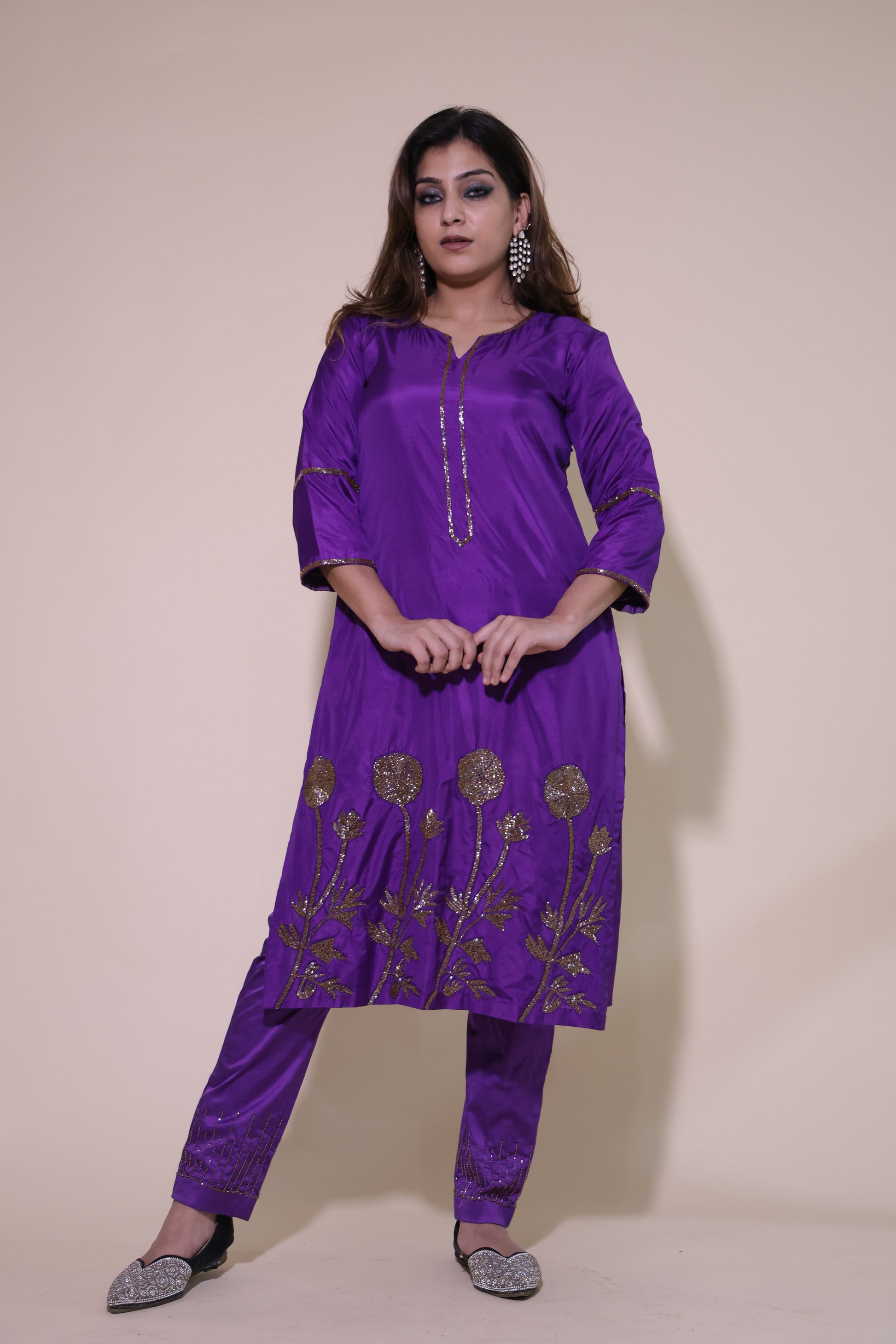 Woman wearing a purple traditional outfit with gold embroidery on a beige background Purple Silk Kurta Set with Cutdana Floral Embroidery